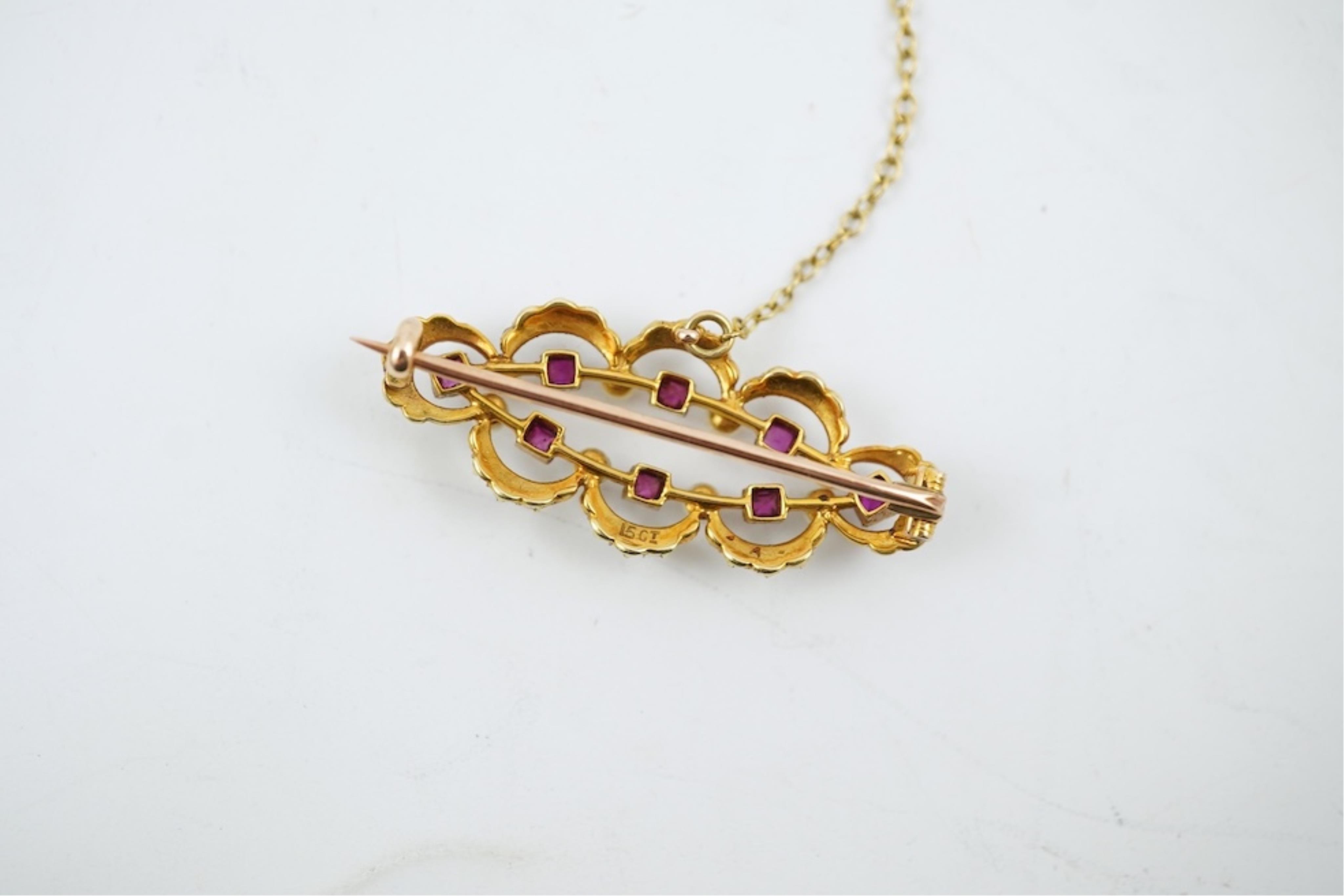 An Edwardian 15ct, ruby and seed pearl cluster set brooch, 33mm, with safety chain, gross weight 4.1 grams.